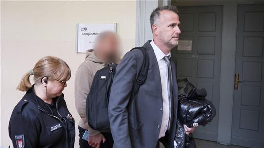 Der Zeuge (Mitte des Bildes) wird von seinem Anwalt (rechts im Bild) in den Gerichtssaal begleitet.