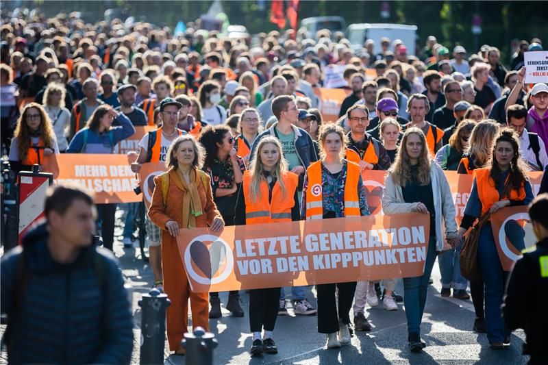 Der Zug einer Demonstration der Letzten Generation zieht von der Siegessäule auf der Straße des 17. Juni Richtung Brandenburger Tor. Aimee van Baalen (am Banner 2.v.l), Sprecherin der Letzten Generation, nimmt ebenfalls teil. Foto: Christoph Soeder/dpa