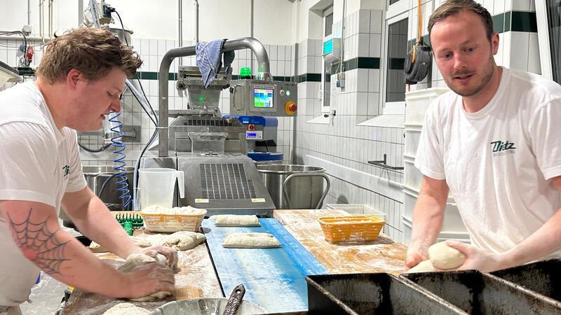 Hand in Hand für frisches Brot: Ein Blick in die Backstube Der angehende Bäckermeister Max Welluhn (links) und Bäckermeister und Juniorchef Jochen Dietz formen die Teigstücke aus der Maschine zu Brotlaiben.