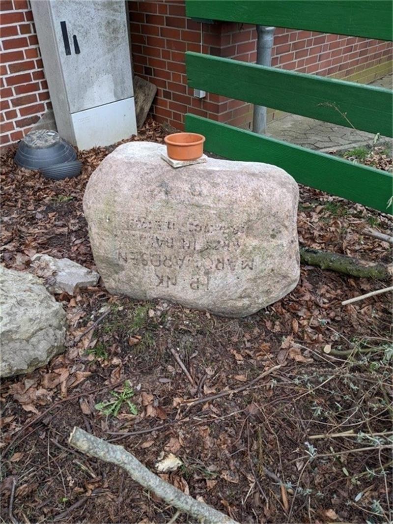 Der auf dem Kopf abgestellte Grabstein, auf dem der Abdruck der gestohlenen Buchstaben deutlich zu sehen ist.