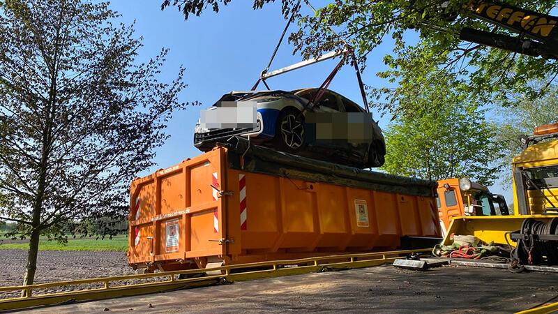 Der ausgebrannte VW ID 3 wird in einen Container gehoben.