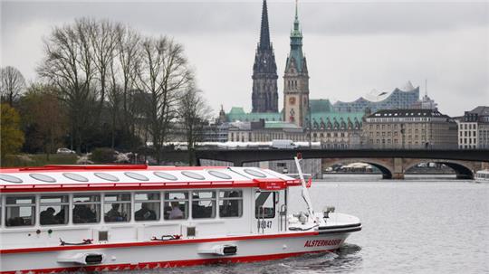 Der batteriebetriebene Dampfer «Alsterwasser» fährt über die Außenalster vor der Innenstadt-Kulisse mit Kirchtum St. Nikolai, Rathaus und Elbphilharmonie. Foto: Jonas Walzberg/dpa