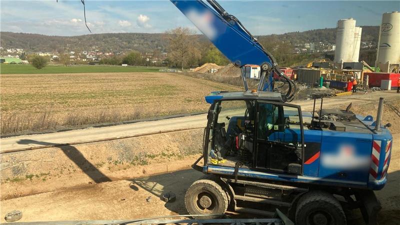 Der beschädigte Bagger steht an einer Baustelle neben den Bahngleisen.