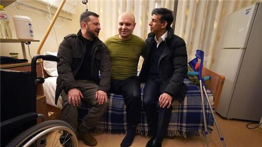 Der britische Premier Rishi Sunak (r) und der ukrainische Präsident Wolodymyr Selenskyj (l) treffen einen verwundeten Kriegsveteranen.