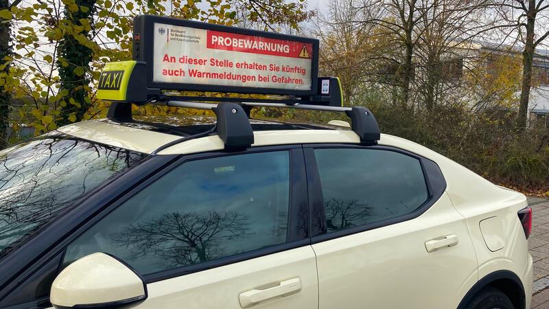 Der eigentlich für Werbung gedachte Dachmonitor auf einem Taxi informiert über eine Probewarnung.