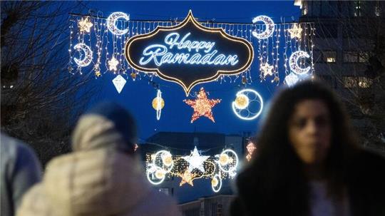Der erleuchtete Schriftzug „Happy Ramadan“ ist bei Einbruch der Dunkelheit auf der Fressgass in Frankfurt am Main zu sehen.