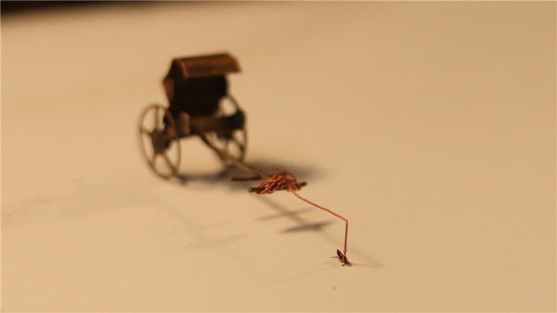 Der etwa drei Millimeter große Floh zieht eine Miniatur-Kutsche.