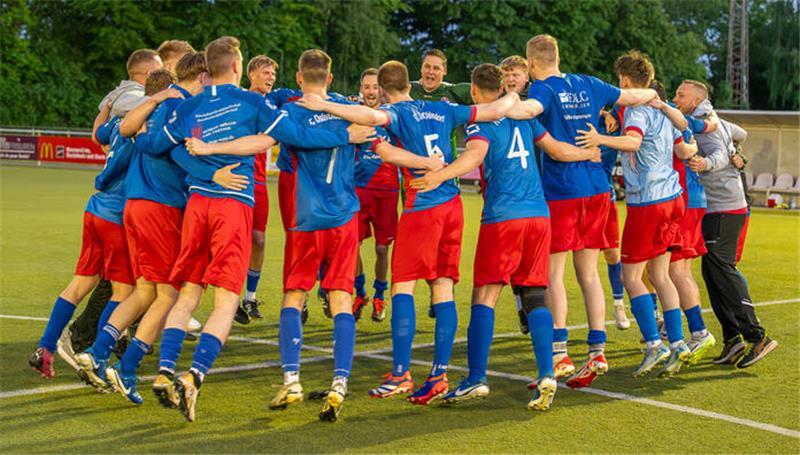 Ein Spielerkreis in rot-blauen Trikots tanzt am Mittelkreis.