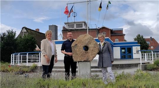 Der historische Ankerstein wurde in Barnkrug wiedergefunden und vor dem Haus der Maritimen Landschaft (mit der Kapitänsbrücke im Obergeschoss) aufgestellt: Petra Schlichting, Sebastian Ipach und Ulrike Mohr (von links) freuen sich über die 