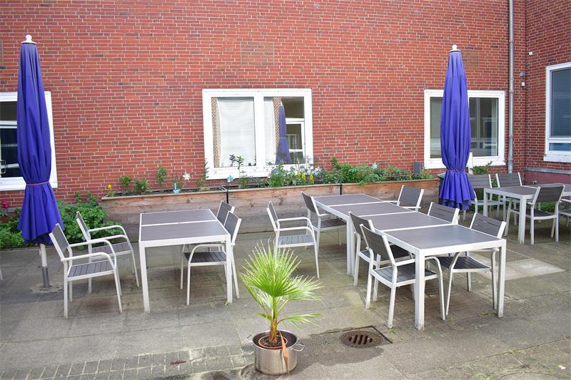 Teamarbeit für gesundes Essen: Sie ernten für die Geestlandschüler Der kleine Innenhof der Mensa mit Sitzplätzen unter freiem Himmel. Neben Hochbeeten mit verschiedenen Kräutern blühen in einem Bodenbeet essbare Rosen. Daraus will die Schülerfirma irgendwann Rosenzucker für ihre Gerichte herstellen, erzählt Dörte Wellm.