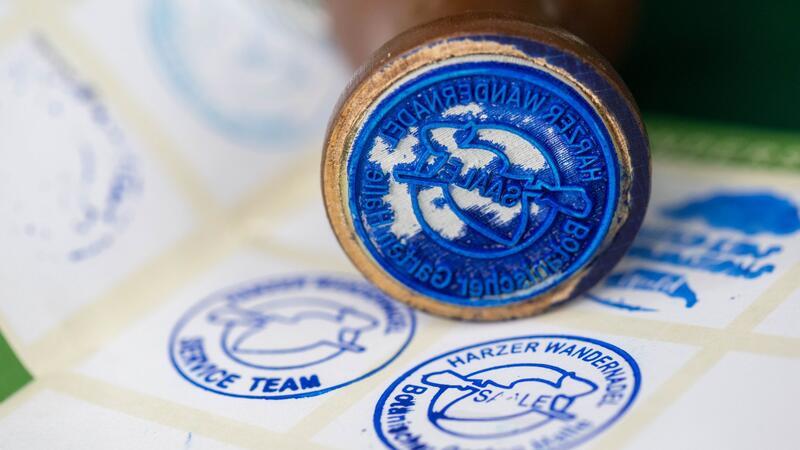 Wandern und Stempel sammeln: Harzer Wandernadel startet Der neue Stempel der Harzer Wandernadel ist vor einem Wanderpass zu sehen.