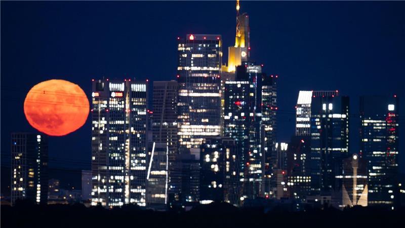 Bilder des Tages Der riesig wirkende „Erdbeermond“ steht über der Bankenskyline von Frankfurt am nächtlichen Himmel.