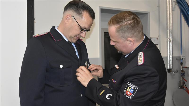 Feuerwehr Apensen: Bewegende Geschichten aus dem Alltag der Retter Der stellvertretende Abschnittsleiter Süd, Sebastian Hinsen, steckt Torsten Plumbohm (links) die Ehrennadel an.