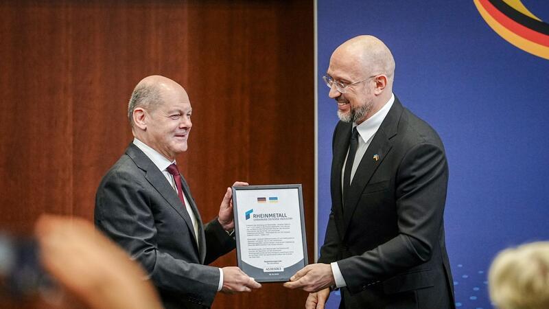Deutsche Wirtschaft will stärker in der Ukraine investieren Der ukrainische Premierminister Denys Schmyhal überreicht Bundeskanzler Olaf Scholz beim 6. Deutsch-Ukrainischen Businessforum der DIHK ein Zertifikat für die Rheinmetall Joint-Venture Registrierung für die Ukraine.