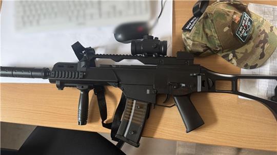 Eine täuschend echt wirkemde Maschinengewehr-Attrappe liegt auf einem Schreibtisch eines Polizisten.  