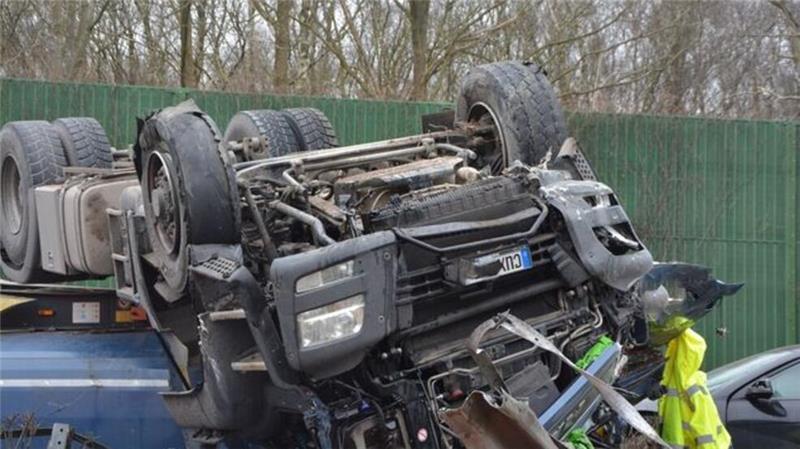 Der verunglückte Lkw liegt auf dem Dach, die Ladung ist über die Fahrbahn verteilt.