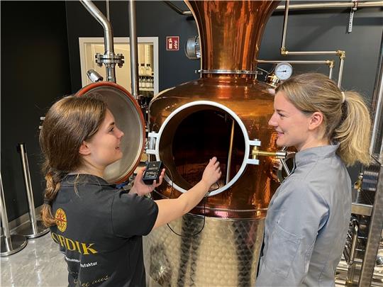 Destillateurin Lea Weßel und Konditorin Annelen Dietz haben gemeinsam einen Franzbrötchenlikör entwickelt (von links). Hier messen sie die Temperatur der Maische in der Brennanlage bei Nordik in Horneburg. Foto: Vasel