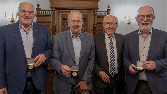 Detlef Maretzki, Rainer Jürgens und Andreas Haack (von links) zeigen ihre Ehrenmedaillen, die ihnen Horst Wartner (Zweiter von rechts) überreicht hat.