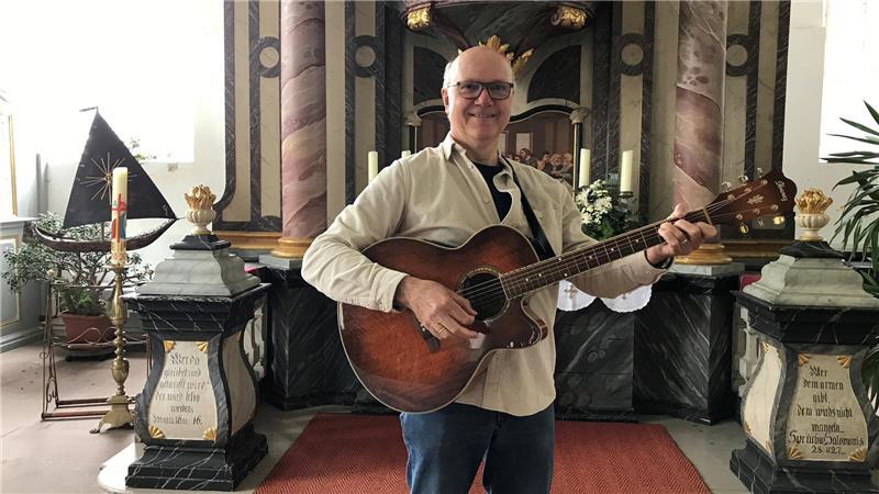 Diakon Andreas Cohrs mit seiner Westerngitarre vor dem Altar der St.-Johannis-und-Catharinen-Kirche in Drochtersen.
