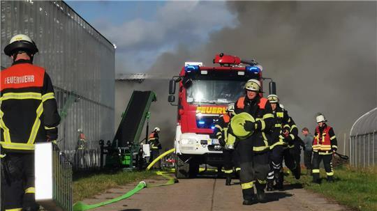 Dichter Rauch steigt aus der Lagerhalle empor, während die Feuerwehrleute versuchen, den Brand zu löschen.