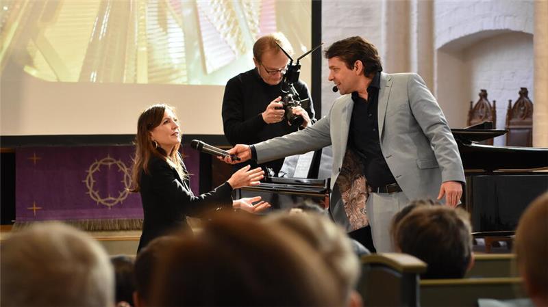 Die Agathenburger Bachtage zu Gast in St. Wilhadi: Moderiert von Kika-Star Juri Tetzlaff, erklärt Pianistin Alexandra Sostmann den Kindern, wie beim Klavierflügel der Ton entsteht.