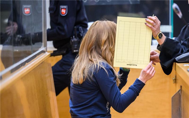 Zwei Kinder sterben – Angeklagte bestreitet illegales Autorennen Die Angeklagte sitzt mit verdecktem Gesicht im Gerichtssaal im Landgericht.