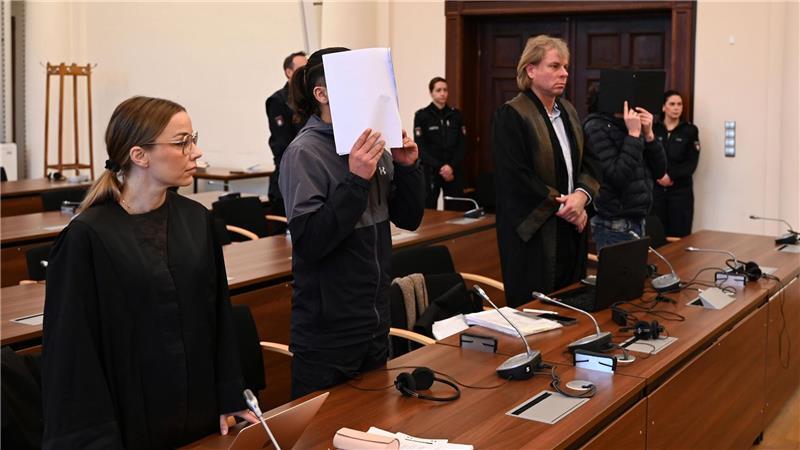 Die Angeklagten halten sich vor Beginn des Prozesstages Dokumente vor das Gesicht.