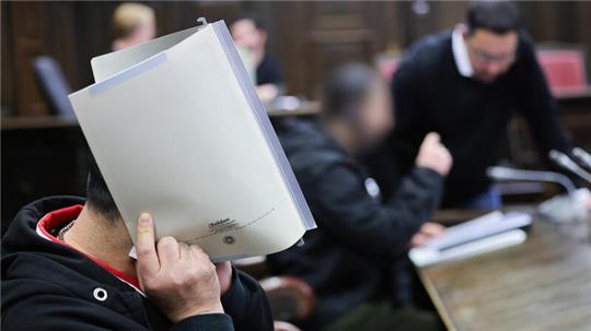 Die Angeklagten (l, und 2.v.r) und ein Dolmetscher vor Prozessbegin im Gerichtssaal im Strafjustizgebäude.