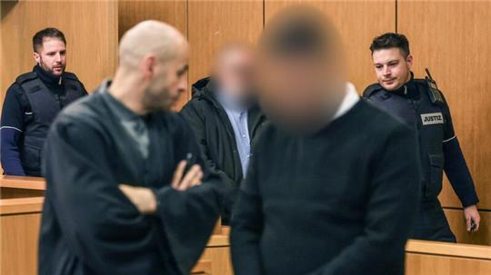 Die Angeklagten werden von Justizbeamten in den Gerichtssaal geführt.