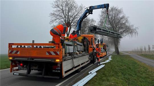 Die Arbeiter laden das Material für den Bau der Leitplanken an der L123 ab.