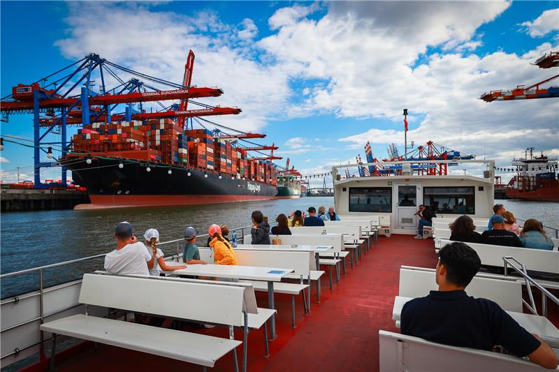 Die Barkasse „Hafen Hamburg“ von Barkassen-Meyer fährt bei ihrer Hafenrundfahrt durch den Waltershofer Hafen neben Containerschiffen die am Containerterminal Burchardkai festgemacht haben. Foto: Christian Charisius/dpa
