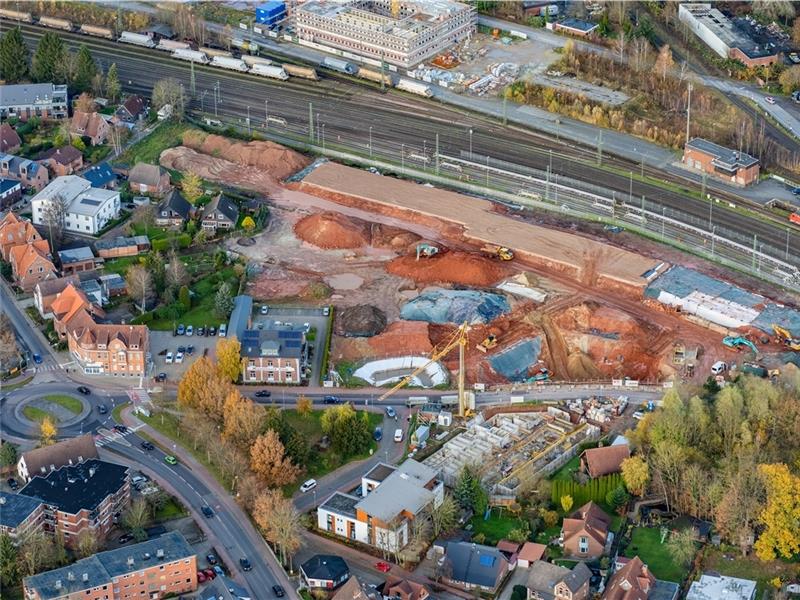 Die Baustelle an der Bahn aus der Luft, links unten der Kreisel Harburger Straße, nördlich der Bahn das Jobcenter im Bau. Auffällig ist die rote Erde. Foto: Martin Elsen