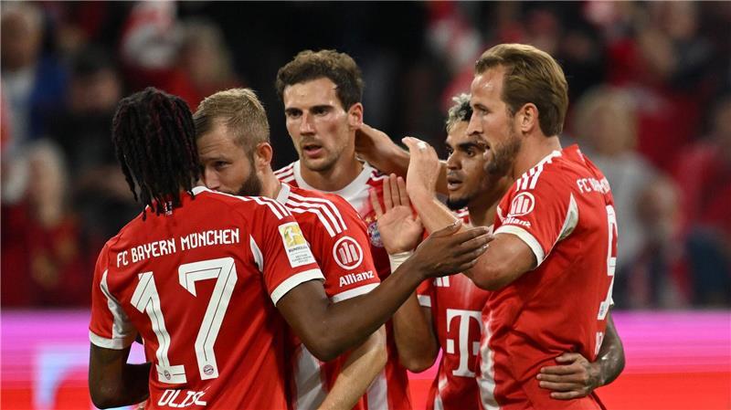 Die Bayern rollen los und feiern mit einem Bosse-Handschlag Die Bayern-Stars haben Spaß miteinander, wie der gemeinsame Jubel der Torschützen Harry Kane (r), Luis Díaz (2.v.r.) und Michael Olise (Nr. 17) zeigt.