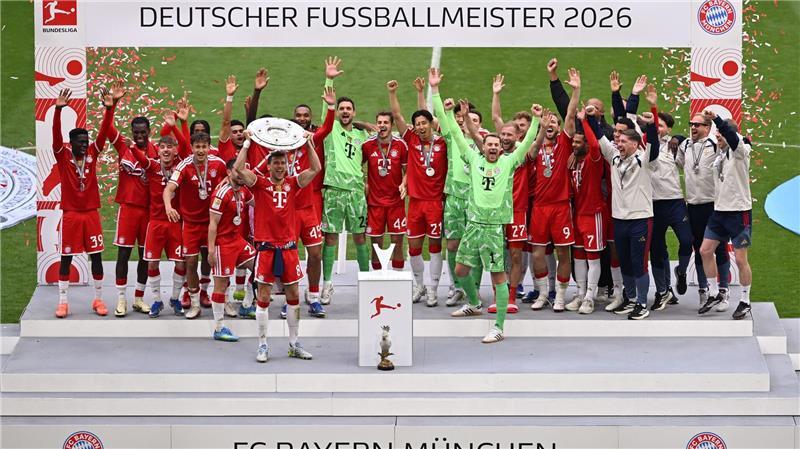 Die Bayern feiern mit der Meisterschale, die Leon Goretzka in Händen hält.