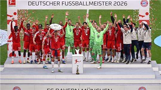 Die Bayern feiern mit der Meisterschale, die Leon Goretzka in Händen hält.