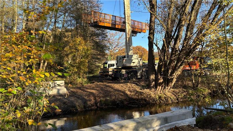 Millimeterarbeit am Kran: Neue Holzbrücke schwebt über die Aue Die Brücke am Wiesenweg schwebte mehrere Minuten über dem Boden.