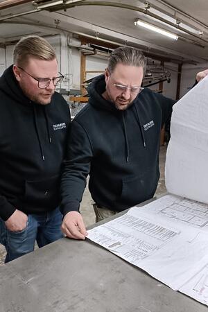 Klintworth-Brüder aus Helmste mit Händchen für Möbel und Särge Die Brüder Klintworth über Konstruktionsplänen einer großen Gebäudeanlage.