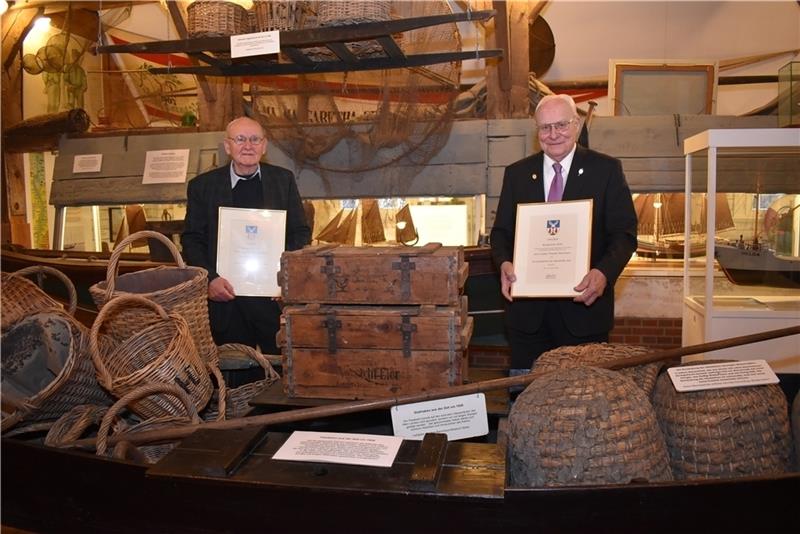Die Bürgerpreisträger 2020 der Gemeinde Jork, Eberhard Becker und Dieter-Theodor Bohlmann (rechts), zeigen ihre Urkunden nach der Verleihung in der in der maritimen Abteilung des Museums Altes Land. Foto: Vasel
