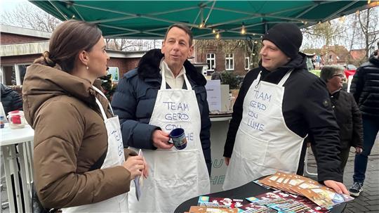 Die Bundestagsabgeordnete Vanessa Zobel und Sven Ehlerding von der Jungen Union nehmen den Bürgermeisterkandidaten Gerd Dehmel (CDU) auf dem Weihnachtsmarkt in Steinkirchen in ihre Mitte.