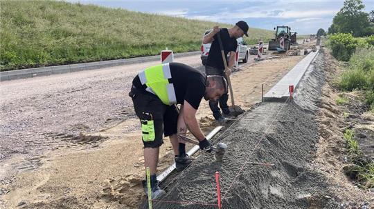 Die Bunte-Straßenbauer Nico Brelage und Julian Wegmann setzen den Bordstein an der K39 in Hinterbrack.