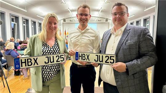 Die Buxtehuder CDU-Stadtratsmitglieder Birgit Butter und Niels Kohlhaase sowie der JU-Vorsitzende Mirco Dawideit (von links) zeigen im Kreishaus Kfz-Kennzeichen mit Buxtehuder Kennung. Die Zahl 25 steht für das Jahr 2025, in dem sich der Wunsch laut CDU erfüllen soll.