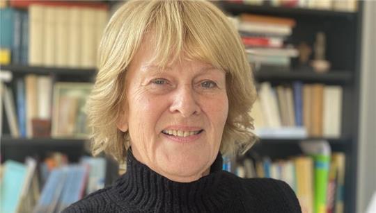 Porträt von Barbara Collet vor einem Bücherregal bei ihr zu Hause