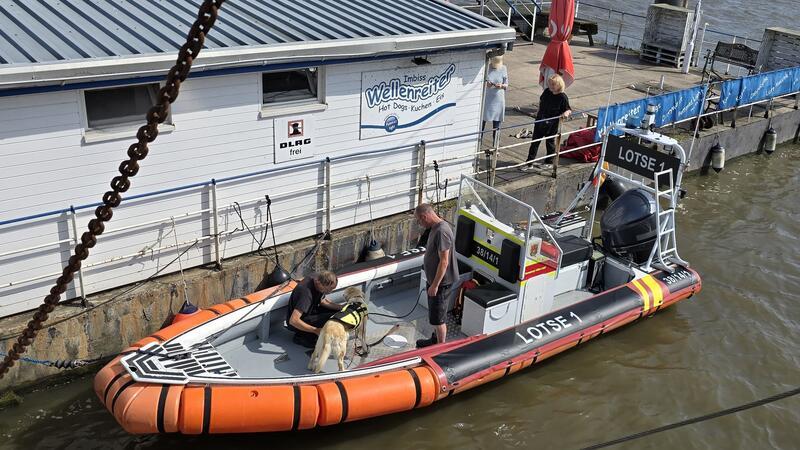 Die DLRG Honeburg bringt in einer Szene eine Lotsin mit einem Hund zum Schiff.