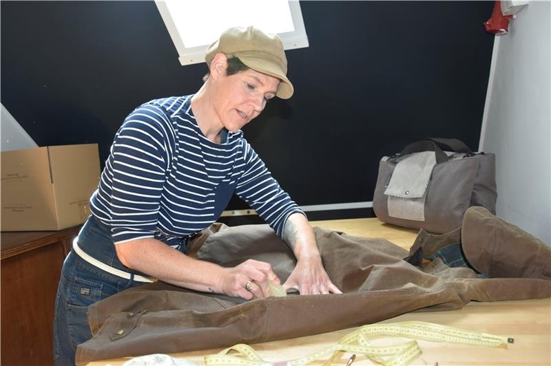 Die Designerin Jennifer Bujko zeigt, wie die Capes gewachst werden, damit sie keine Feuchtigkeit durchlassen. Foto: Felsch