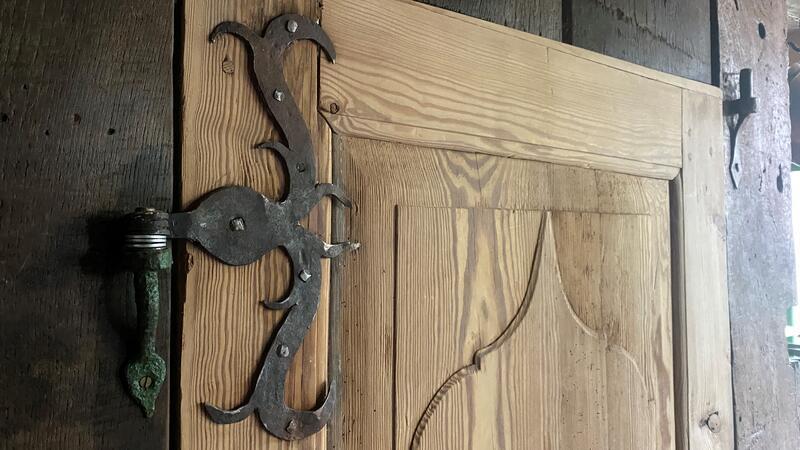 Alte Gemäuer: So lebt es sich im sanierten Bauernhaus Holztür mit großem Metallbeschlägen, die wie Ranken anmuten.