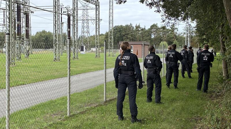 Stromnetz-Saboteure oder Metalldiebe: Polizei auf der Pirsch in Dollern Die Einsatzkräfte suchen entlang des Zauns den Außenbereich ab, sie werfen auch einen Blick in die Baumkronen.