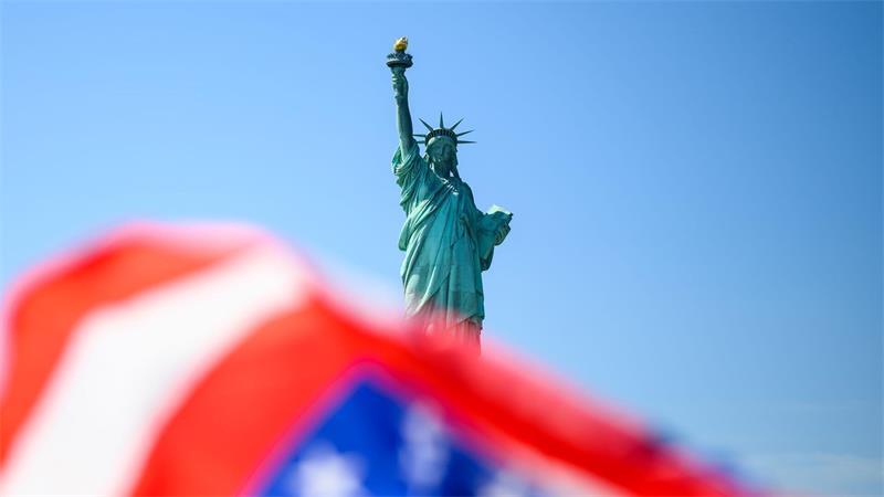 Die Fahne der USA weht vor der Freiheitsstatue.
