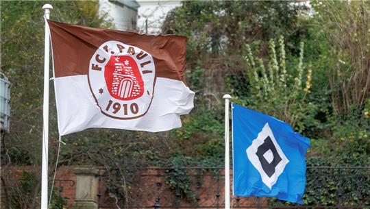 Die Fahnen der beiden Hamburger Bundesliga Profi-Fussballclubs wehen nebeneinander an zwei Masten. Foto: Markus Scholz/dpa