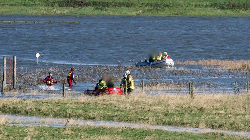 Eine Familie mit zwei Kindern wird von Rettungskräften nach einer Wanderung in den Salzwiesen mit Schlauchbooten ans Ufer gebracht. 