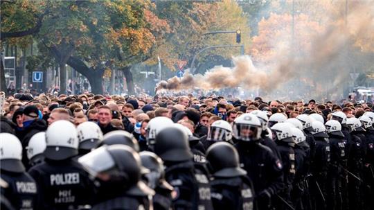 Die Fans des Hamburger SV gehen von der Polizei begleitet zum Stadion und brennen Pyrotechnik ab.